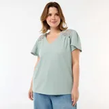 Camiseta color verde menta de tejido crepé con escote en V y mangas cortas acampanadas. Presenta detalles de encaje de macramé en los hombros.