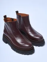 Bota corta de cuero negro, estilo botín chelsea, con puntera cuadrada y suela track gruesa y robusta.
