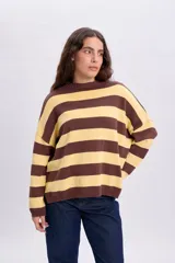 Buzo tejido oversize de manga larga con diseño de rayas horizontales en color amarillo y marrón, cuello redondo y hombros caídos.