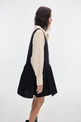 Vestido corto negro de algodón, con escote en V cruzado, sin mangas y falda con fruncido en la cintura.