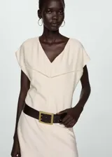 Vestido corto de color crudo con cuello en pico, manga corta y detalle de bordado calado en el pecho. Presenta un diseño evasé y cierre de cremallera invisible en la parte posterior.