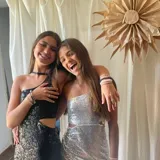 Vestido corto asimétrico con un hombro descubierto y dos breteles finitos que se atan cruzados en la espalda. El vestido es de lentejuelas plateadas y tiene un corte en la cintura.