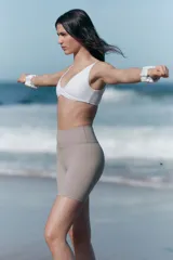 Top deportivo blanco para yoga, con escote en V, breteles anchos y detalle girado en el frente. Incluye copas forradas con relleno extraíble.