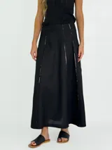 Pollera larga de lino color blanco, con corte acampanado y paneles verticales con costuras a la vista.