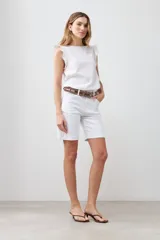 Bermuda de jean color blanco, con cinco bolsillos, corte a la rodilla y cierre frontal con botón y cremallera.