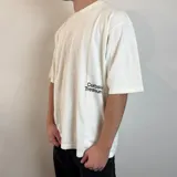 Remera color hueso con estampado de hongos y texto en la espalda, corte oversize.