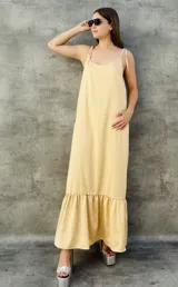 Vestido largo color beige, de breteles finos con lazo y falda con volados.