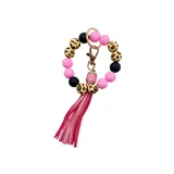 Llavero pulsera con cuentas de silicona negras, rosas y con estampado animal print. Incluye un fleco de cuero sintético rosa y un aro metálico dorado.