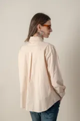 Camisa color crema de manga larga con dos bolsillos frontales con solapa.