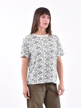 Remera de manga corta color beige con estampado de bananas en tonos amarillo, naranja y rosado.