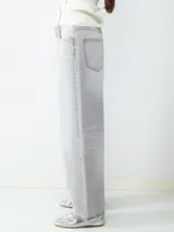 Jean de tiro alto color gris claro, corte loose con pernera ancha. Diseño clásico de cinco bolsillos con cierre de cremallera y botón metálico.