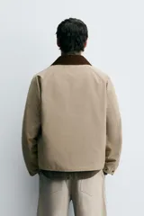 Cazadora de corte relajado confeccionada en tejido técnico con algodón. Presenta cuello de solapa en pana a contraste, cierre frontal con cremallera oculta por solapa con botones a presión, bolsillos de vivo en la cadera y manga larga.