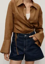 Short de jean de tiro alto con diseño recto, cinco bolsillos, cierre frontal con cremallera y botón, y trabillas para cinturón.