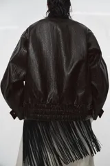 Chaqueta de cuero sintético con textura rugosa, cuello alto con trabilla, cierre frontal con cremallera y botones a presión, bolsillos delanteros y bajo ajustable con hebilla metálica.
