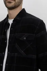 Camisa de pana color azul marino, con mangas largas, cuello clásico y dos bolsillos frontales con solapa y botón.