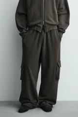 Pantalón cargo de corte relajado con efecto lavado, confeccionado en tejido de algodón. Presenta cintura elástica, bolsillos laterales de plastrón con solapa y bolsillos delanteros.
