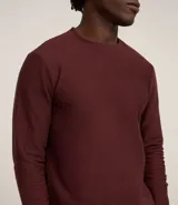 Remera de manga larga con cuello redondo y textura acanalada, confeccionada en una mezcla de poliéster y algodón.