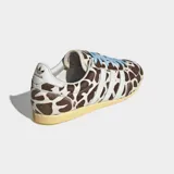 Championes Adidas modelo Japan con diseño de perfil bajo, exterior de cuero con acabado de pelo de poni y estampado animal print tipo jirafa. Presenta las icónicas tres tiras laterales en blanco, cordones en color celeste y suela de caucho en tono amarillento.