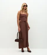 Pollera midi de sastrería color marrón, con cintura estructurada, trabillas y lazo frontal en cordón. Presenta un corte recto y fluido.
