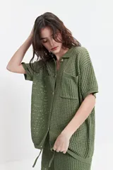 Camisa tejida color borgoña con textura calada, cuello clásico, botones y mangas cortas con elástico.