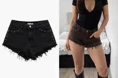 Short de jean negro con ruedo desflecado y detalle de tachas metálicas en forma de estrella en los bolsillos delanteros.