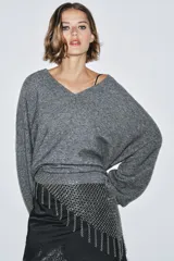 Cinturón plateado tipo malla de anillas metálicas con flecos colgantes y cierre con mosquetón.