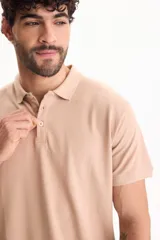 Chomba de piqué color blanco, con cuello polo y cierre frontal con tres botones.