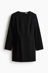 Vestido corto de sarga color negro con escote redondo, hombreras y manga larga. Tiene cintura entallada, bolsillos ribeteados con solapa y cierre oculto en la espalda.