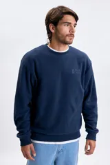 Buzo de polar azul marino con cuello redondo, mangas largas y puños elásticos. Presenta un bordado sutil en el pecho con la frase Jungle Bungle.