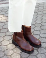 Botinetas de caña baja confeccionadas en cuero vacuno color chocolate, con paneles laterales en gamuza al tono. Presentan suela track de goma negra, cierre lateral interno y puntera redondeada.