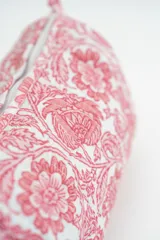 Neceser de tela acolchada con estampado floral en tonos rosados sobre fondo blanco, con cierre superior y estructura rectangular.