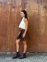 Minifalda tipo pareo confeccionada en cuero color chocolate, con diseño cruzado y cierre mediante tiritas laterales ajustables.