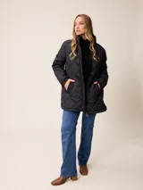 Campera larga acolchada con diseño de rombos, cierre frontal completo y cuello alto. Presenta puños elásticos y un pequeño logo aplicado en el pecho.