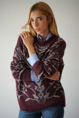 Buzo de tejido de punto en color marrón con un patrón ornamental floral en color celeste. Presenta cuello redondo, mangas largas y un corte holgado.