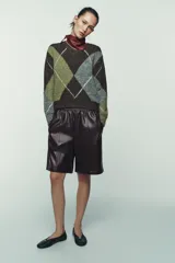 Bermuda de tiro alto confeccionada en material efecto piel, con cintura elástica y costuras verticales decorativas en el frente.