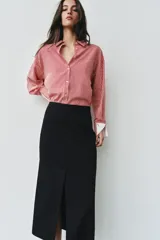 Camisa de cuello solapa y manga larga con rayas verticales rojas y blancas, con puños anchos blancos contrastantes y cierre frontal de botones.