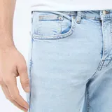 Pantalón de jean corte slim, color azul claro con efecto lavado, cierre frontal con botón y cremallera, y bolsillos laterales y traseros.