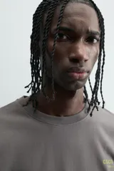 Camiseta de manga corta y cuello redondo, color gris oscuro con efecto lavado. Presenta un pequeño estampado en el pecho con texto en color verde lima.