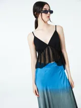 Top negro con breteles finos y detalle de volado de tul en el busto.