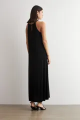 Vestido largo negro de lurex, con escote halter y diseño fluido y acampanado.