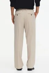 Pantalón de vestir color beige, de corte relajado, con bolsillos laterales y traseros, y raya marcada en las piernas.
