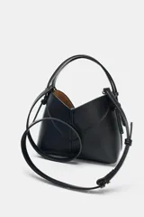 Mini bolso tipo shopper confeccionado en material trenzado color beige, con detalles en cuero sintético marrón. Cuenta con asa de mano fija y correa bandolera extraíble, además de una cartera interior con cierre.