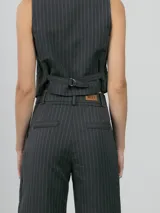 Chaleco sastrero color beige, con escote en V, cierre frontal con botones y bolsillos laterales decorativos.