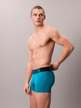 Pack de tres bóxers tipo trunk Calvin Klein, confeccionados en una mezcla de poliéster reciclado y elastano. Presentan una cinturilla elástica distintiva con el logo de la marca y un diseño de pierna corta para mayor comodidad y ajuste.