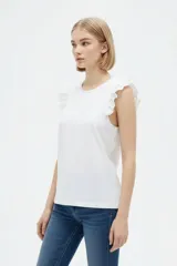 Remera de algodón color blanco, de corte al cuerpo, con cuello redondo y detalles de volados en las sisas.