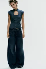 Top entallado de efecto denim, con cuello subido, manga corta, cierre frontal con botones y una llamativa abertura circular en el pecho.