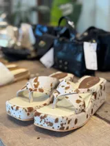 Sandalias con plataforma y capellada de cuero con estampado animal print de vaca en tonos marrón y blanco.