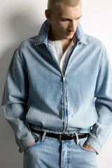 Cazadora de denim de algodón con efecto lavado, corte cropped, cuello solapa, cierre frontal con cremallera de doble dirección, manga larga con puños abotonados y bolsillos laterales.