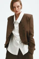 Camisa oversized blanca con finas rayas verticales beige, de manga larga y cierre frontal con botones.