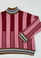 Buzo oversize de punto con cuello alto, mangas largas y diseño a rayas verticales en tonos rosa y bordó.